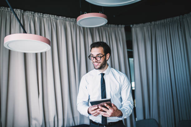 istock Close up of businessman using tablet while standing in lobby. 1068881342