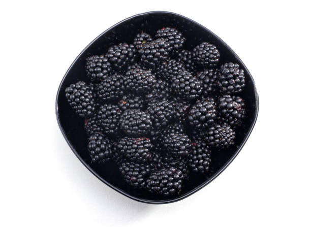 close up pile of clean fresh blackberries fruit in fruit cup over white background