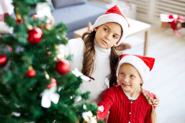 istock Girls by xmas tree 1068890944