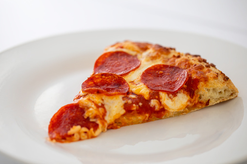 Slice of pepperoni pizza on a white plate