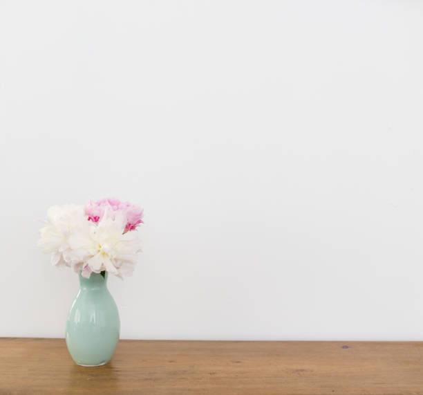 istock Pink and white peonies in green vase on table 1068901524