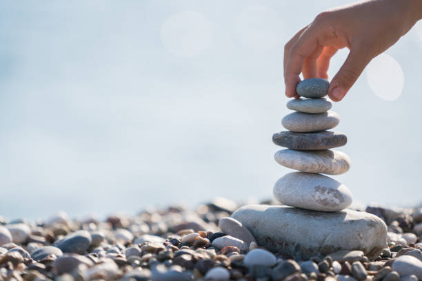 child hand balancing stack of stones on beach - balance simplicity nature beach imagens e fotografias de stock