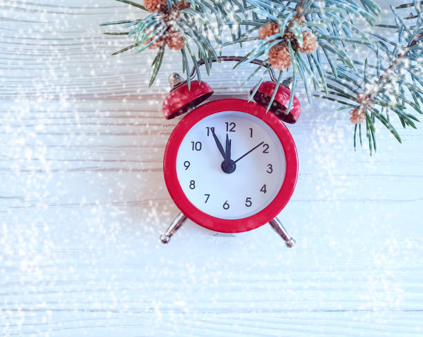 istock Christmas tree branch alarm clock on wooden snow background 1068904006