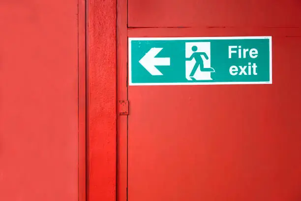 Fire exit sign on building evacuation red door uk