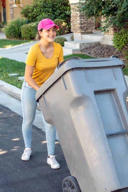 istock Smiling young woman wearing a pink cap pushing a garbage bin 1068909728
