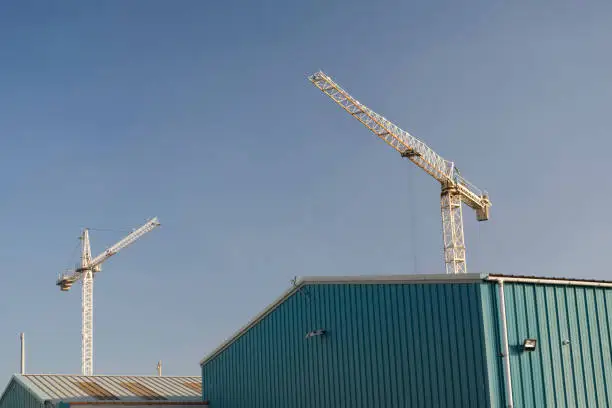 Twin tower crane white in empty blank blue sky at construction building site uk