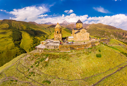 Beautiful Top view from drone to Tsminda Sameba or Holy Trinity Church Near Village Of Gergeti In Georgia and of the high mountain Kazbek, Caucasus mountains. Public place to visit.