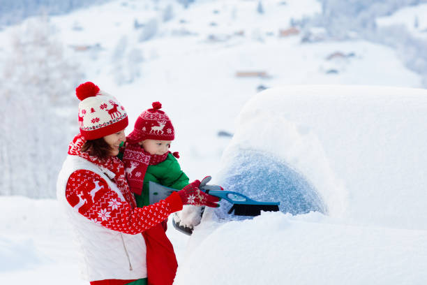 Mother and child brushing off car in winter.