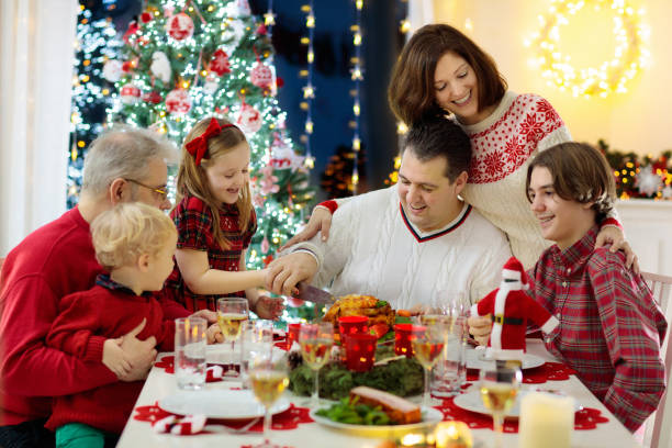istock Family with kids having Christmas dinner at tree 1068937736