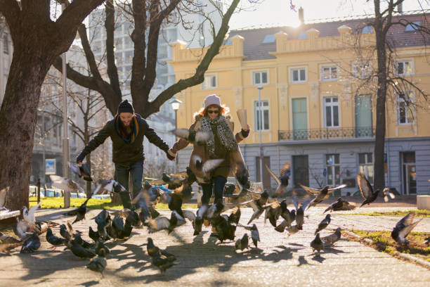 istock Young couple running through pigeons in the park 1068954396