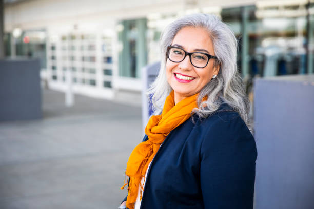 Senior Hispanic Woman waiting outside the airport A Senior Hispanic Woman waiting outside the airport for a taxi or to board a plane. 55 59 years stock pictures, royalty-free photos & images