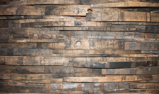 Closeup of a portion of a ​wall built up with wine barrel wooden strips in a variety of widths.