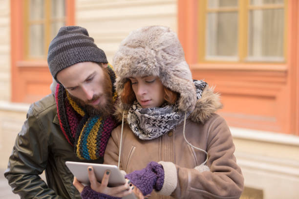 istock Young couple with winter hats browsing through street directions on a tablet 1068965744