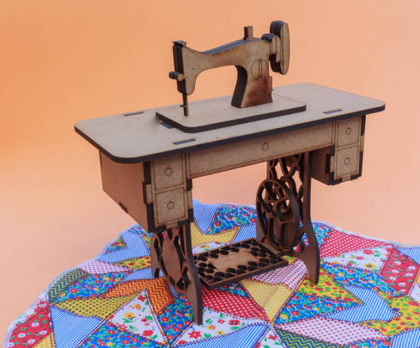 istock Mini sewing machine, made of wood, on a patchwork rug, with yellow background. 1068971884