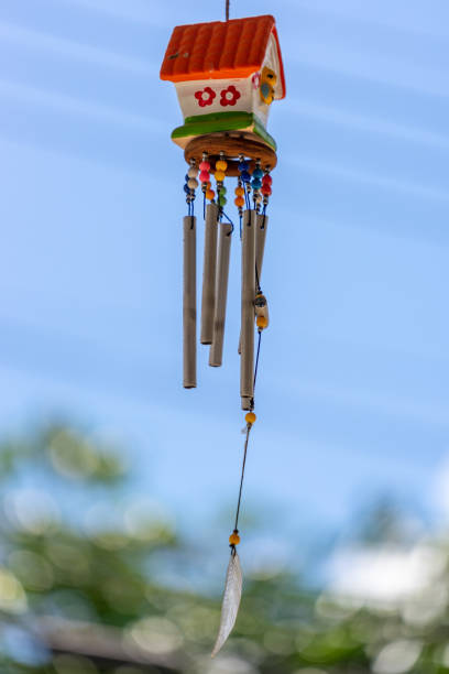 istock Small house outdoor mobile hanging with small bell, sounding when wind moving hanging in front of the house with blurred sky background and electrical line. 1068983118