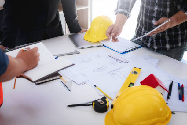 istock engineer people meeting working and pointing at a drawings house in office for discussing. Engineering tools and construction concept. 1069008890