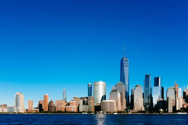 Photo of Skyline of downtown Manhattan over Hudson River under blue sky, at sunset, in New York City, USA