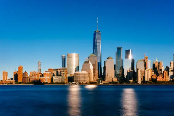 Photo of Skyline of downtown Manhattan over Hudson River under blue sky, at sunset, in New York City, USA