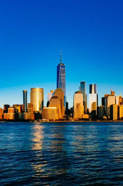 Photo of Skyline of downtown Manhattan over Hudson River under blue sky, at sunset, in New York City, USA