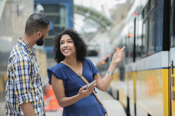 istock Young commuter couple are talking while using a phone and waiting for train 1069023444