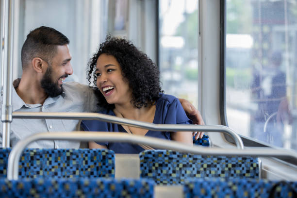 istock Diverse young couple sits and laughs while riding public transportation. 1069023546