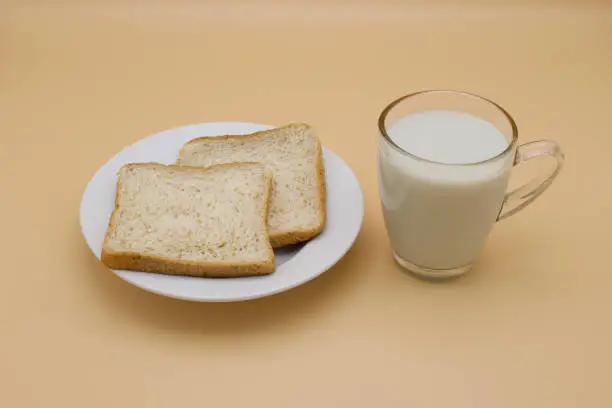 Whole wheat bread on a plate with a cup of soy milk