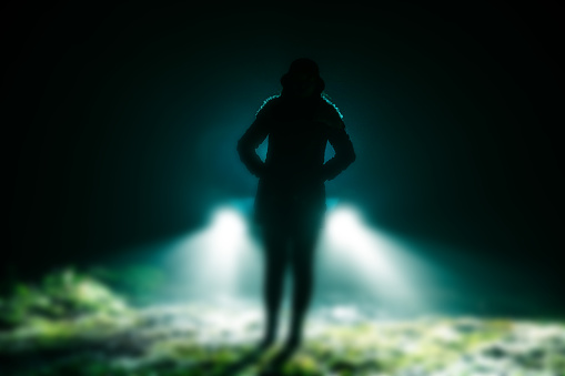 Woman standing in front of car at night in mist
