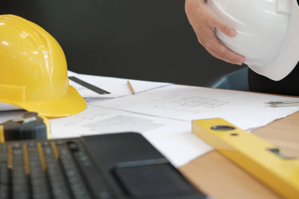istock engineer architect worker holding safety helmet hardhat wtih construction blueprint on desk 1069030916