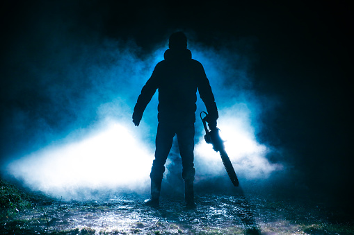 Man holding chainsaw at night