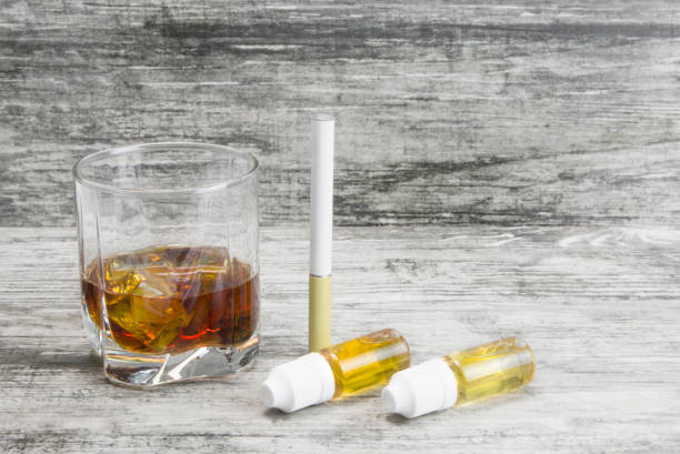 istock Not a full glass of alcoholic whiskey drink with an e-cigarette on a marble surface.Bad habits harmful to health 1069034344