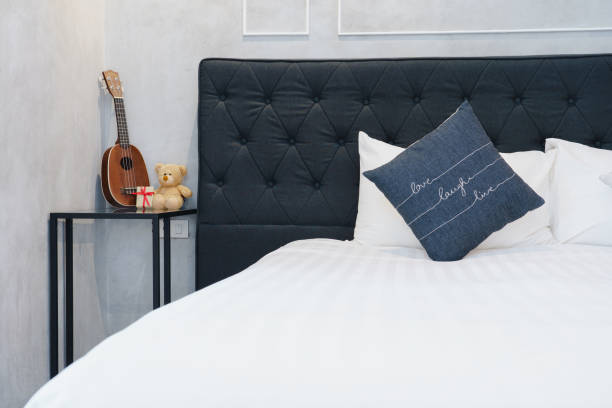 istock Minimalist bedroom with black white and gray color pillows, ukulele and teddy bear on modern bedside table. 1069043452