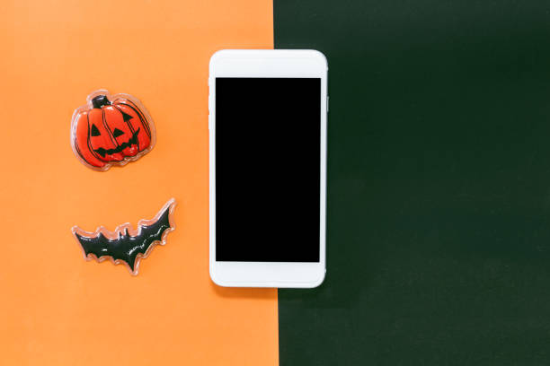 istock Smartphone with black bat and pumpkin on orange and black background.halloween day and decoration concept 1069047052