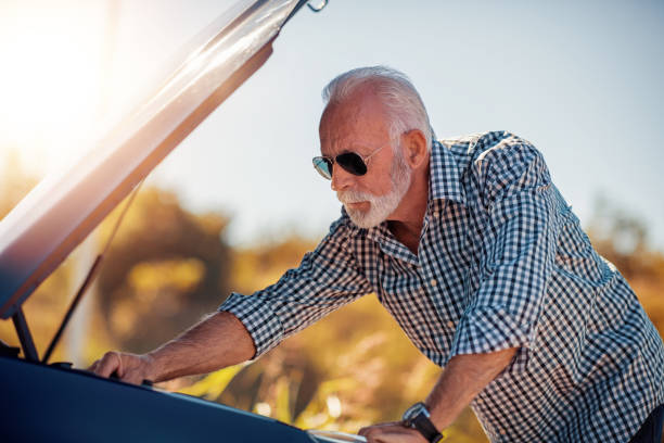 senior man looking under car hood, close up - vehicle breakdown hood car oil change imagens e fotografias de stock