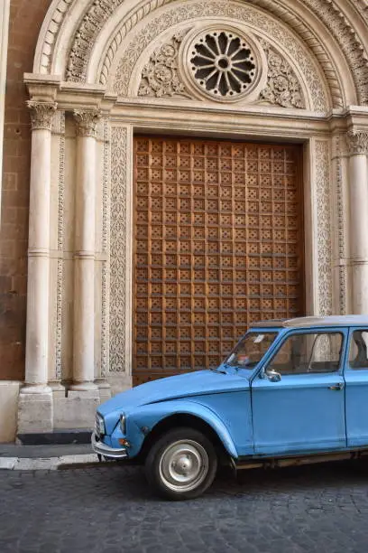 Vintage Citroen car parked on the street in Rome, Italy in front of a large ornate door