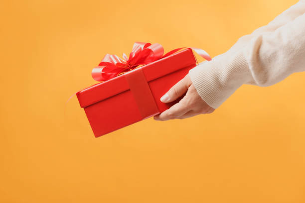 istock close-up partial view of man in sweater holding red gift box on 1069065360
