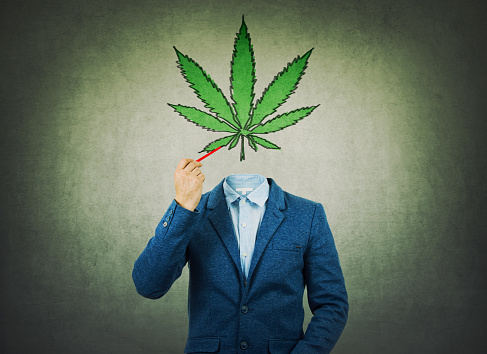 Surreal image as a businessman with invisible face holding a pencil in his hand draw marijuana leaf symbol instead of head. Cannabis legalization as medical drug. CBD healing social issue concept.