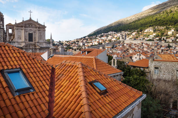 View over the roofs of Dubrovnik and church St. Stepan with green mountains in the background, Croatia View over the roofs of Dubrovnik and church St. Stepan with bell tower with green mountain in the background, Croatia fort minceta dubrovnik stock pictures, royalty-free photos & images