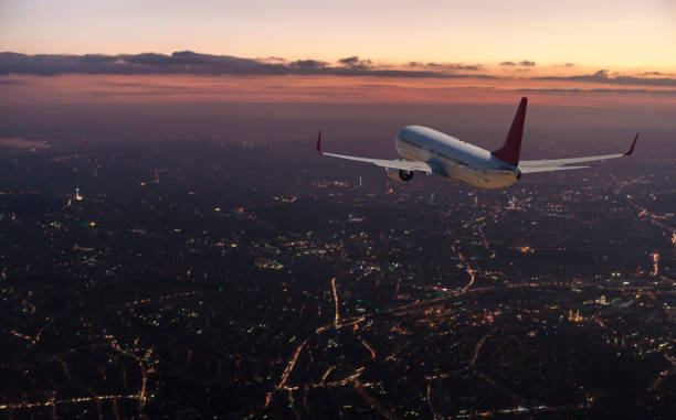 Commercial airplane flying over big city at dusk