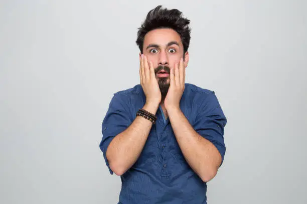 Photo of Portrait of shocked young man over grey background