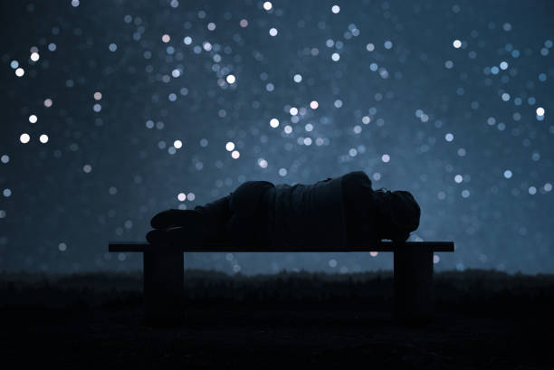 A man sleeping on a bench. Forest and starry sky bokeh In the background