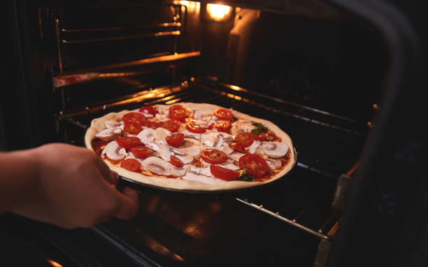 istock Cook's hand immerses pizza in the oven 1069106510