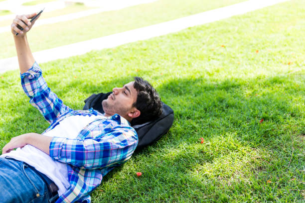 istock Teen using Smartphone to take Selfie while lying down at the campus lawn 1069111414