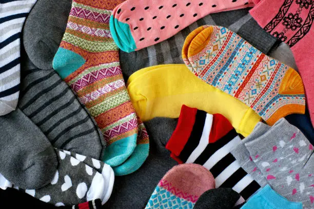 Many colorful socks form a textural background. Socks of different types and sizes.