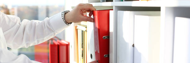 istock Male arms pick red file folder from office book shelf 1069114448