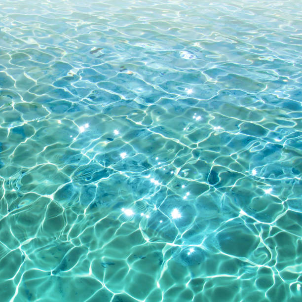 istock Blue transparent water surface with bright sun glare and sunny shining reflections on bottom. 1069119458