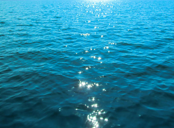 istock Bright blue rippled water surface and shine of sun glare on waves. 1069119500