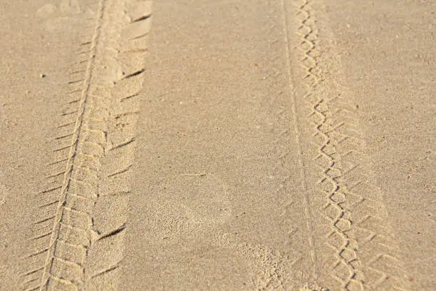 Traces on the sand from a motorcycle or motobike. Traces from the protectors.