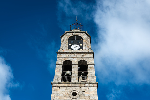 Low-angle view of the main tower of Santa Maria del Azogue roman church in Puebla de Sanabria against a cloudy blue sky, Spain, built in gothic style in the XXII century.