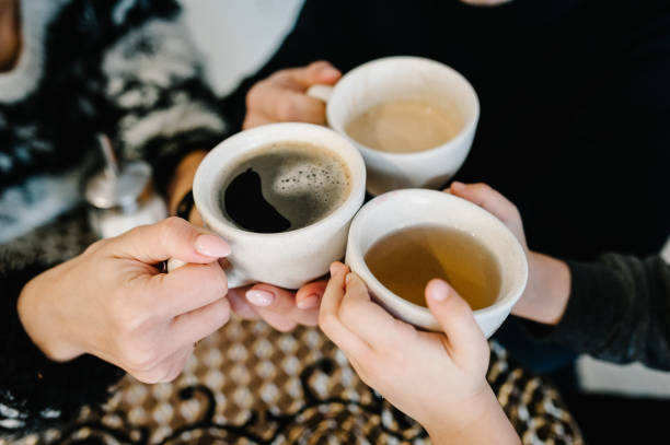 manos sostienen las tazas con café y té en la mañana. feliz madre, padre e hijo desayunando en la cocina en casa. concepto de familia, comer y personas. vista superior. - té bebida caliente fotografías e imágenes de stock