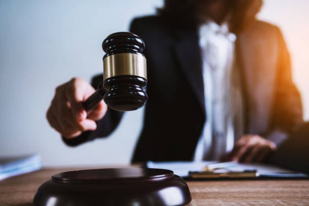 法廷で食卓に弁護士の木製小槌を持っているクローズ アップ手。正義、法律、弁護士、裁判所の裁判官、コンセプト。 - gavel judge human hand court ストックフォトと画像